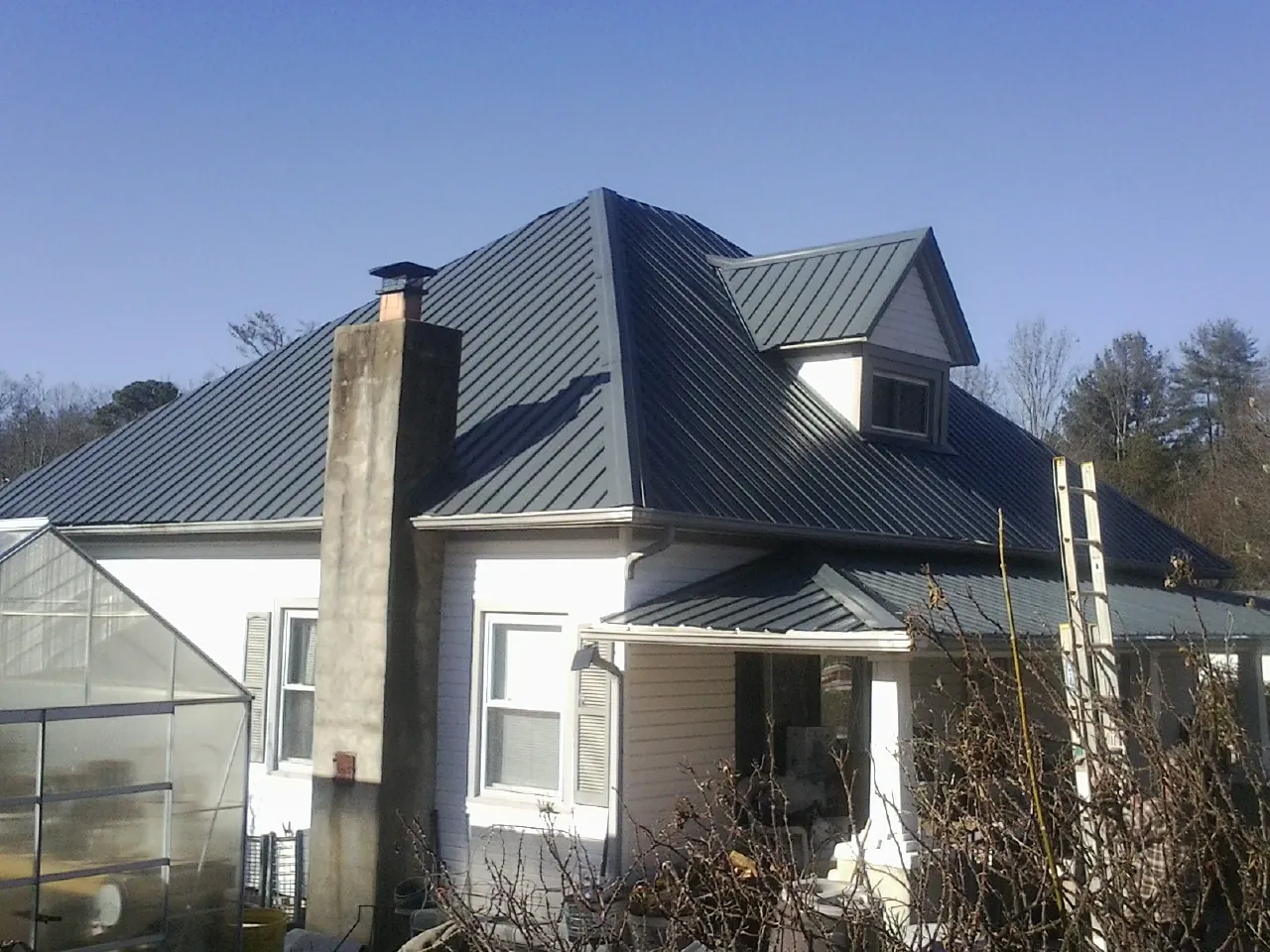 Dark blue standing seam metal roof on a white farmhouse with dormer — Slate & Tile Roof Repair by Roofing Brothers in Paulsboro