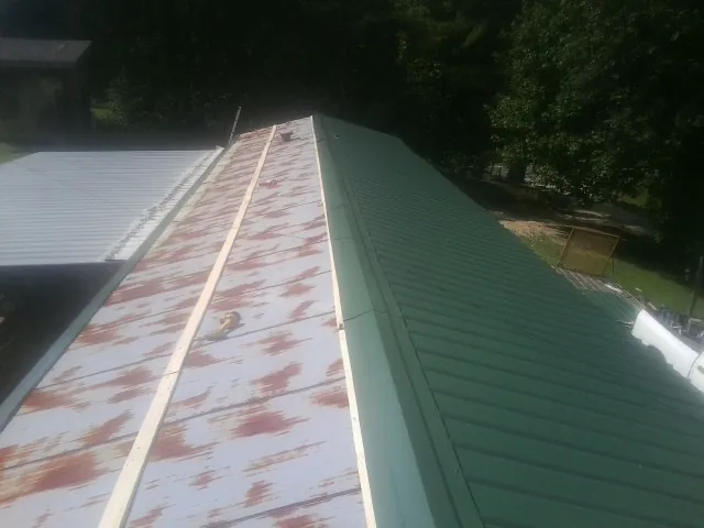 Old rusted panels beside newly installed green metal roofing — Wind Damage Roof Repair by Roofing Brothers in Paulsboro