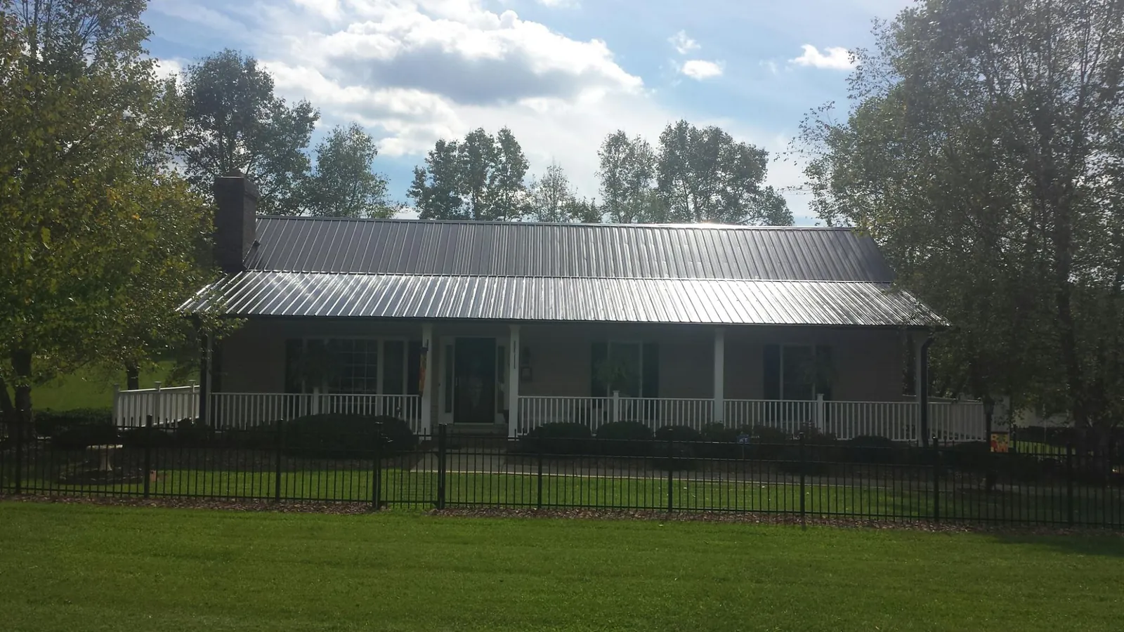 Gray metal roof on a brick ranch with a full width front porch — Gutter Guard Installation work by our crew in Paulsboro