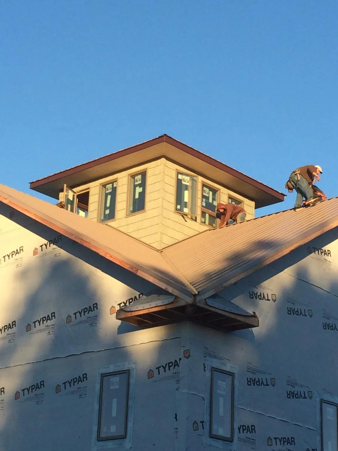 Roofers working around a rooftop cupola on a new metal roof at sunset — Roof Waterproofing in Paulsboro by Roofing Brothers